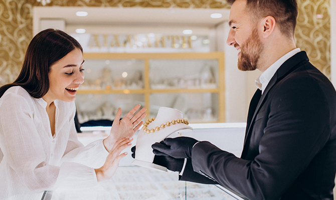 Plano Gold and Silver Exchange customer viewing a gold necklace presented by a jeweler in a jewelry store, showcasing professional service and luxury gold jewelry selection.