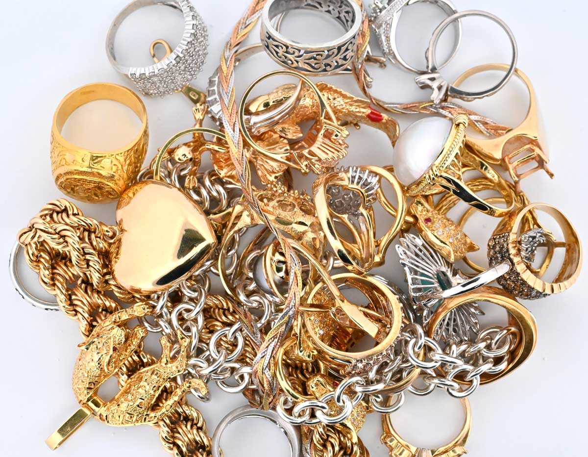 Assorted gold and silver rings and chains displayed for Cash 4 Gold services